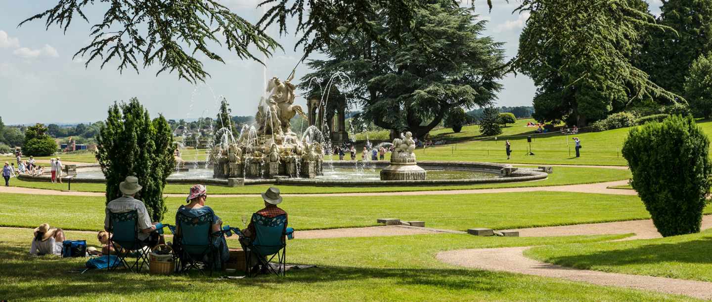 Photo of people sat in camping chairs and on the ground in front of the Perseus & Andromeda fountain at Witley Court and Gardens