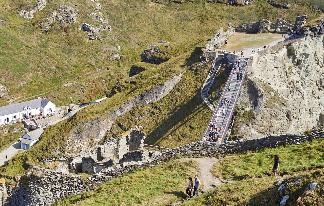 A view of Tintagel Castle showing the stone ruins, new bridge connecting the island to the mainland and steps up to the ruins
