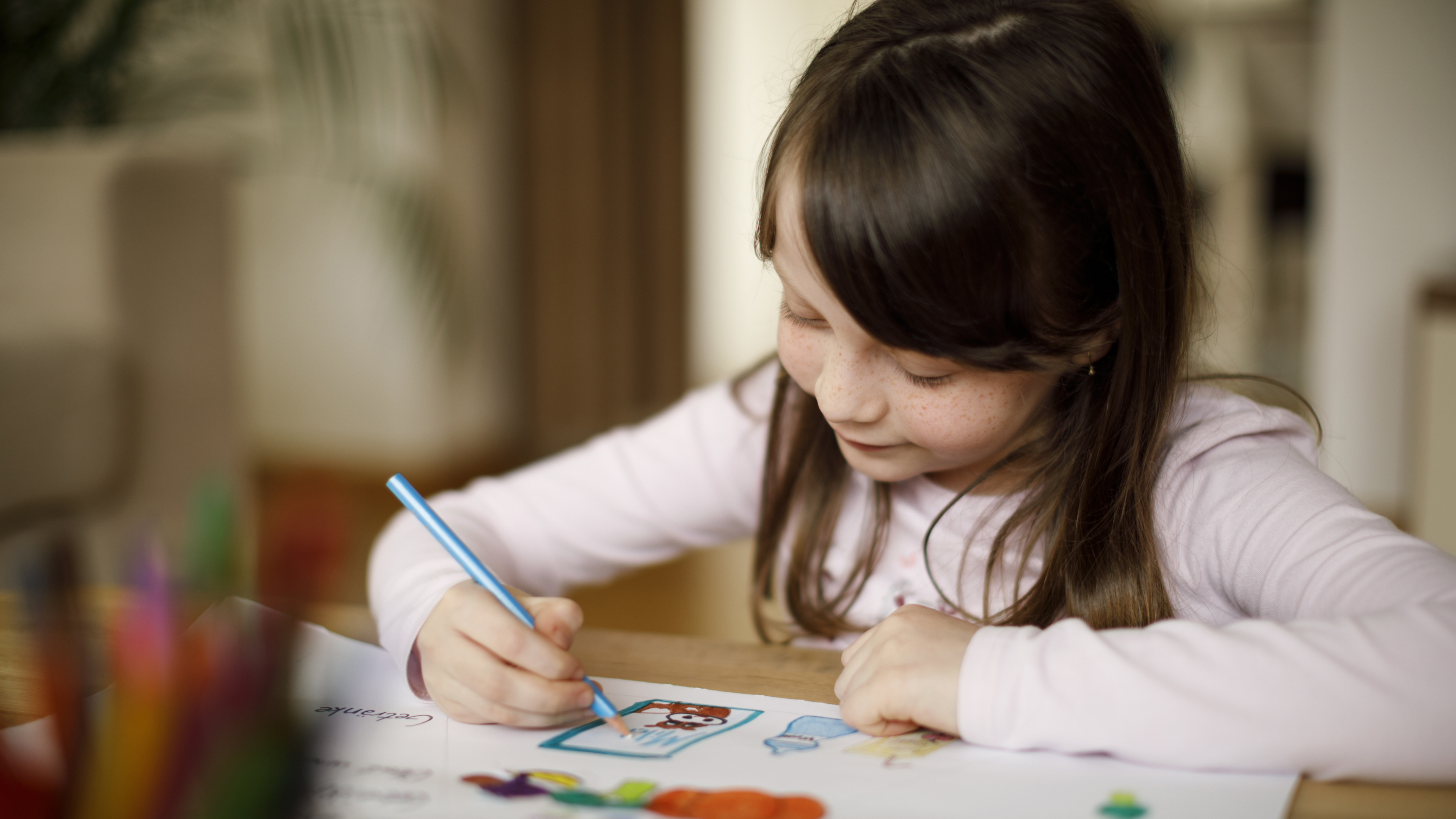 A young girl smiling and drawing a picture