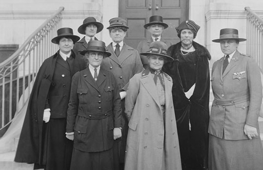 Black and white photograph of eight women in military uniforms or smart clothes standing on the steps - Maud McCarthy is centre front
