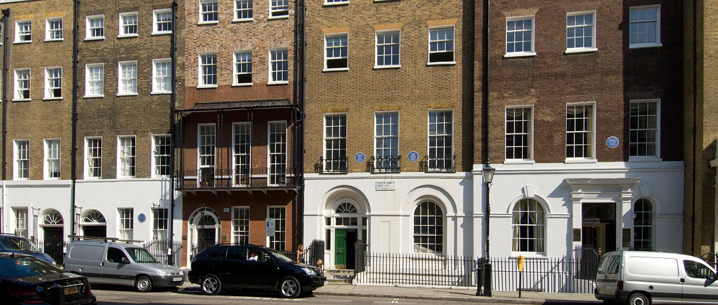 View of terraced brick housing with four blue plaques visible