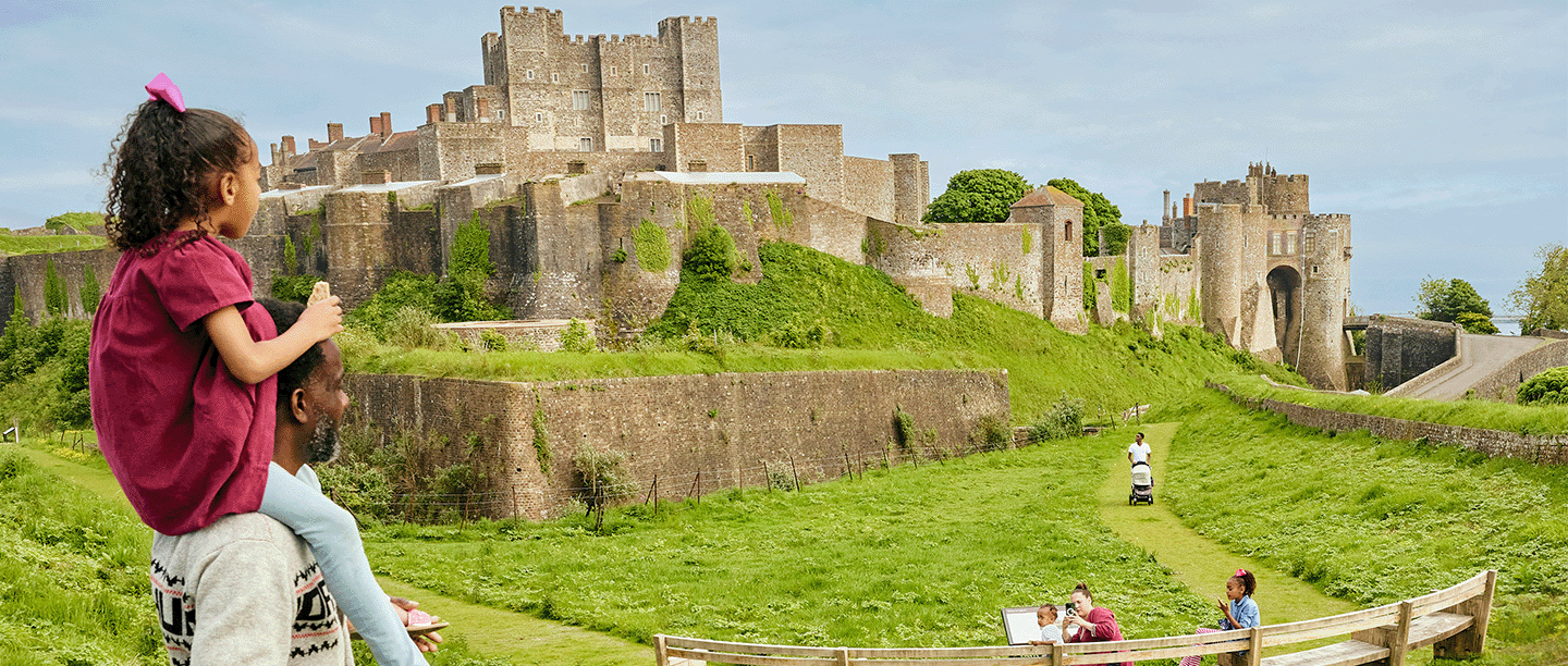 Photo of a child on an adult's shoulders looking out at Dover Castle