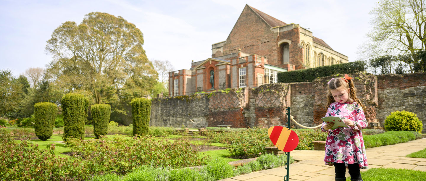 A girl reads an Easter trail leaflet outside Eltham Palace