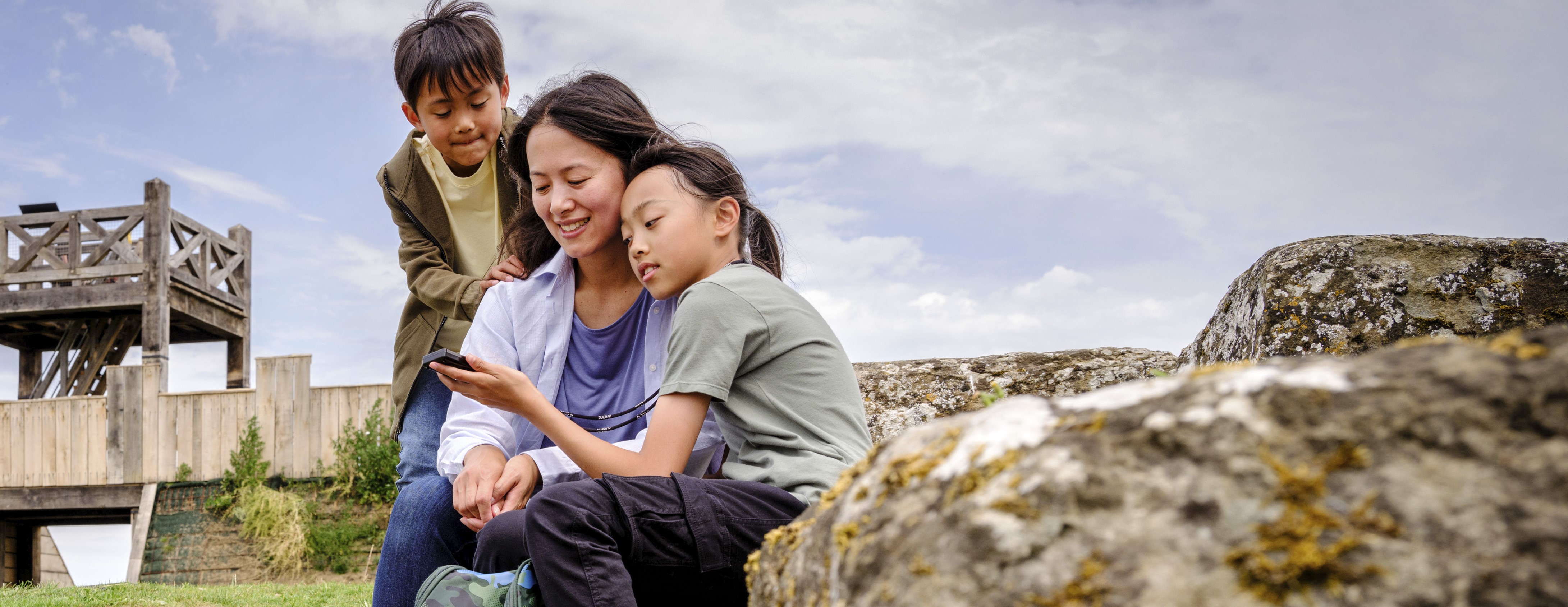 Photo of an adult and two children looking at a smartphone at Richborough Roman Fort