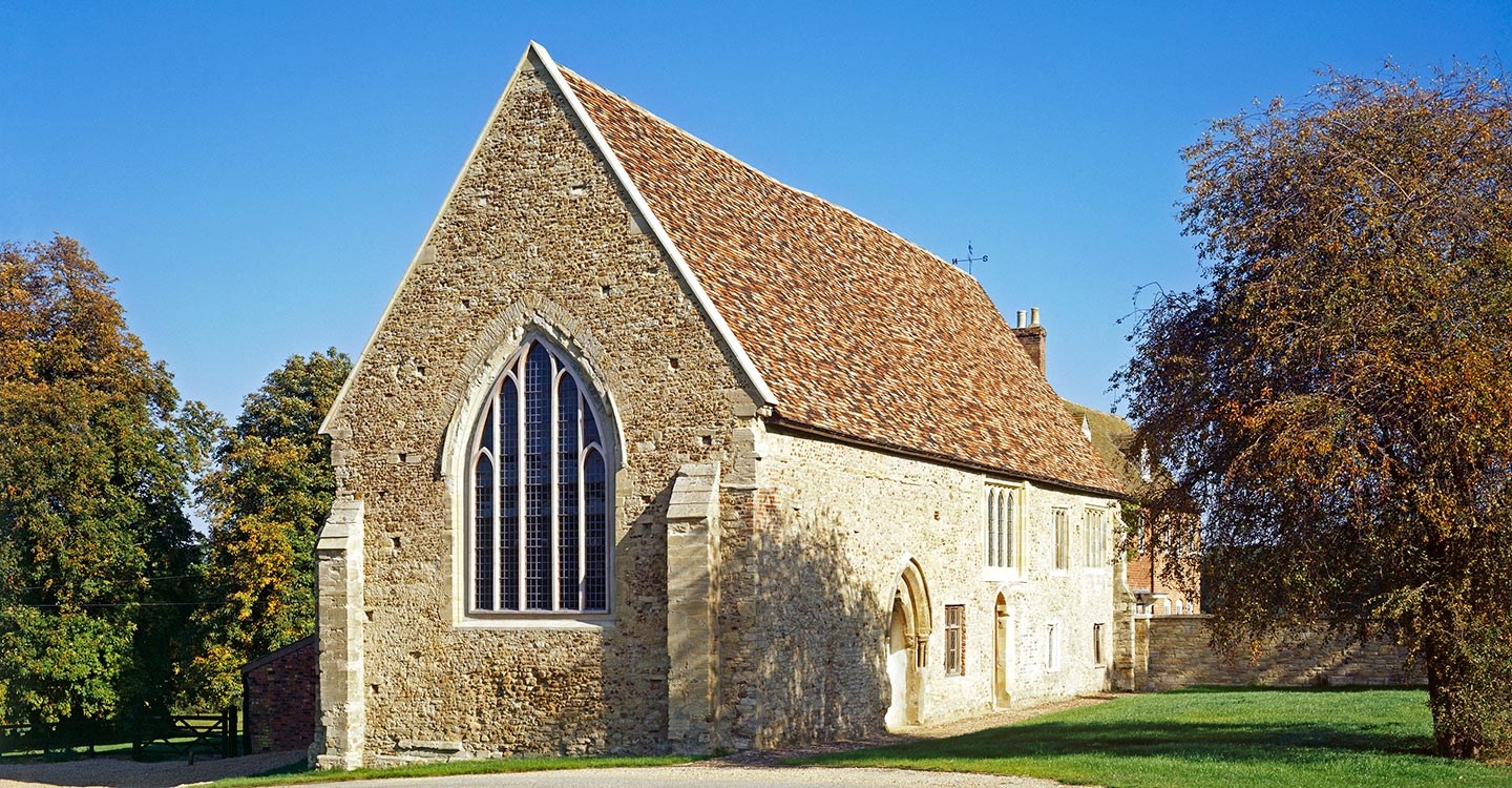 Exterior photo of Bushmead Priory surrounded by trees on a sunny day
