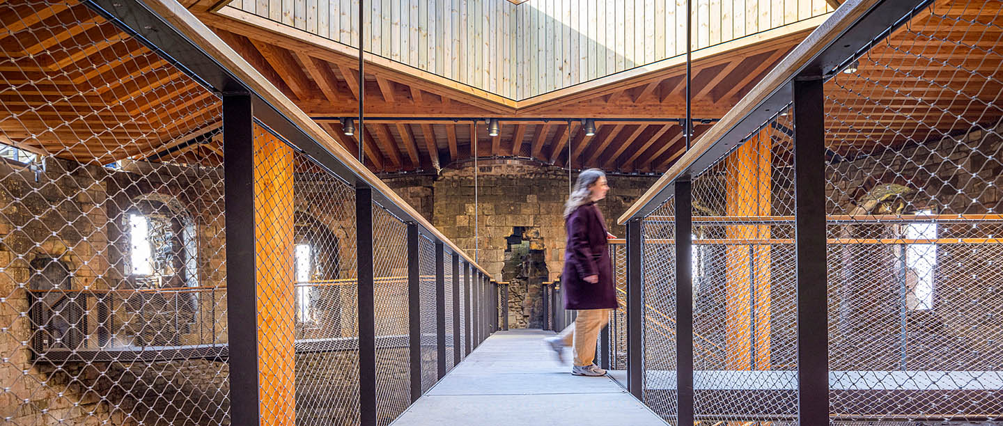 A visitor crosses a raised walkway at Clifford's Tower