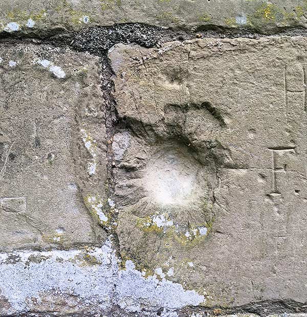 Damage to the castle wall near the main entrance, which may have been caused by enemy fire
