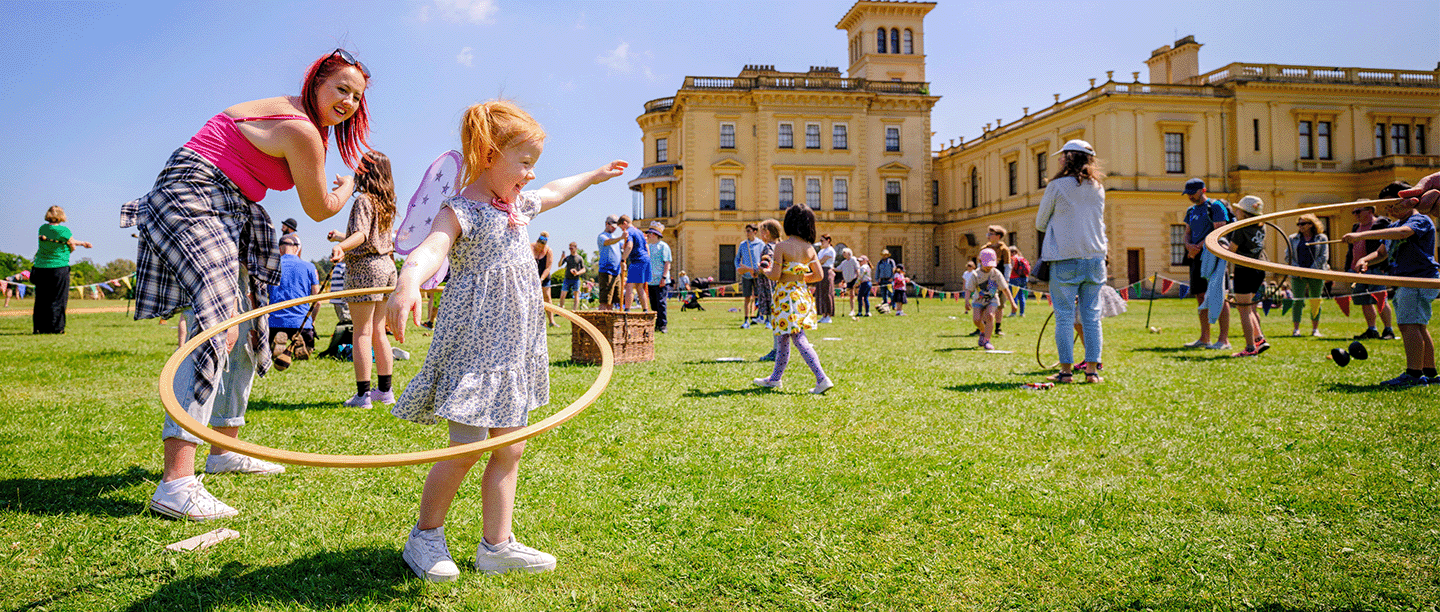 Photo of a young child playing with a hula hoop in the grounds of Osborne on a sunny day